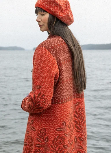A woman wearing an orange long cardigan from Gudrun Sjödén.