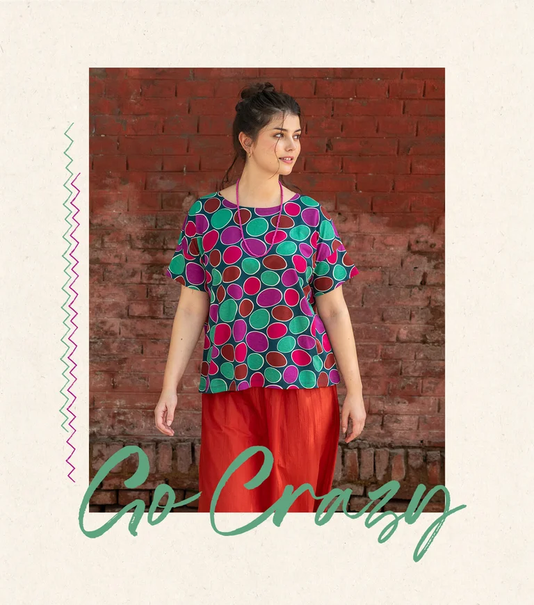 En kvinna klädd i prickig topp och röd kjol från Gudrun Sjödén.