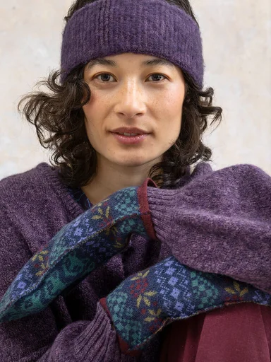 A woman wearing a knit headband and patterned mittens from Gudrun Sjödén.