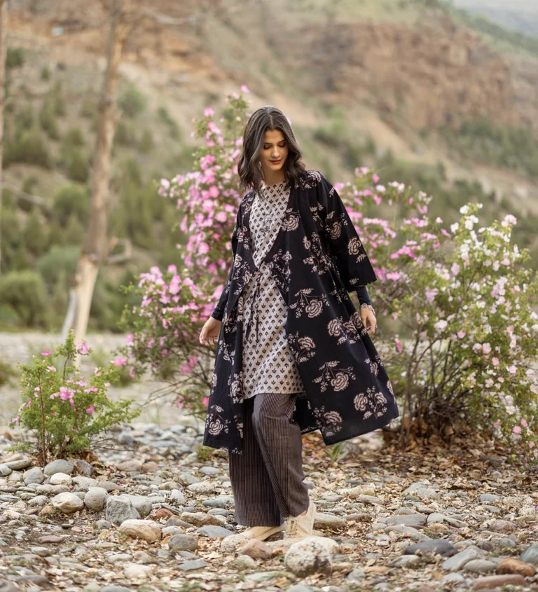 A woman wearing a patterned dress, wrap dress and pants from Gudrun Sjödén.