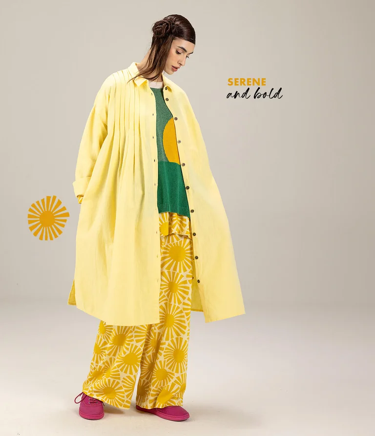 A woman wearing yellow and green clothing in layers from Gudrun Sjödén.