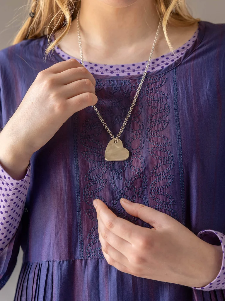 Un plan serré sur une femme portant un vêtement à empiècement brodé et un collier en argent provenant de la collection de Noël 2025 de Gudrun Sjödén.