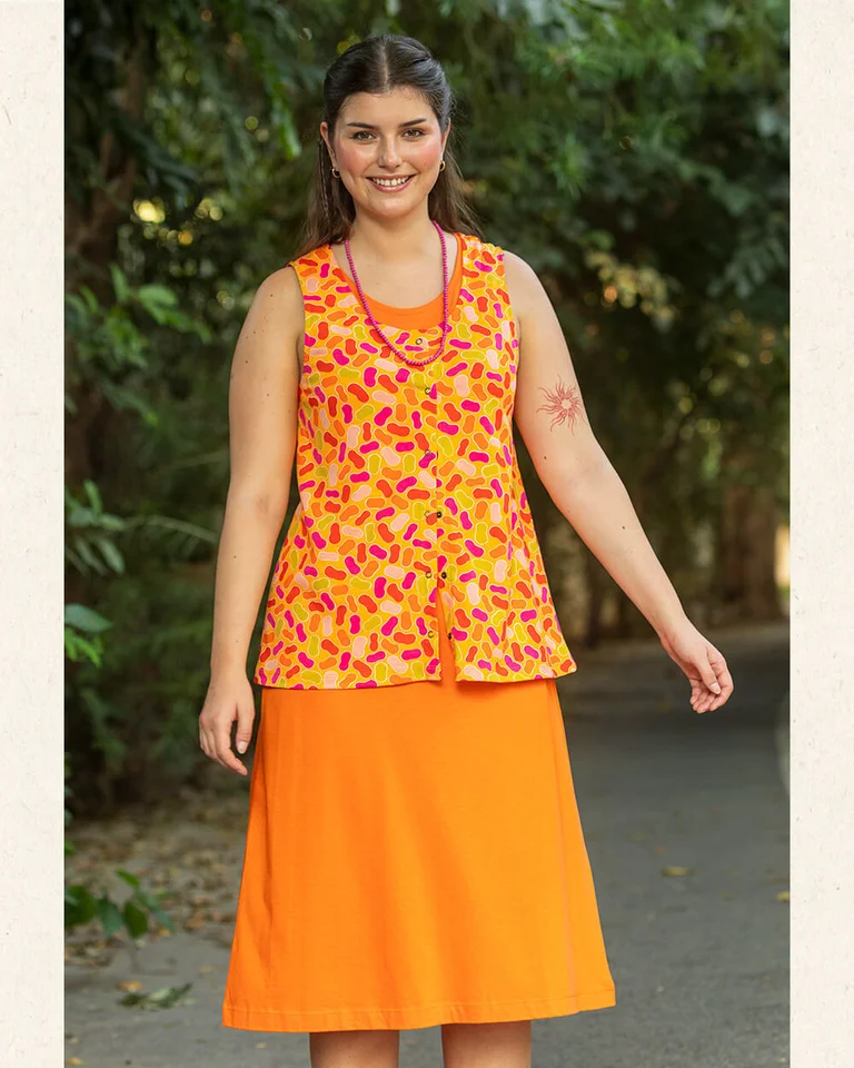 A woman wearing an orange dress and patterned tank top from Gudrun Sjödén.