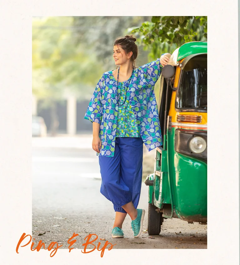 Een vrouw gekleed in een blauwe broek en een gedessineerde blouse van Gudrun Sjödén.