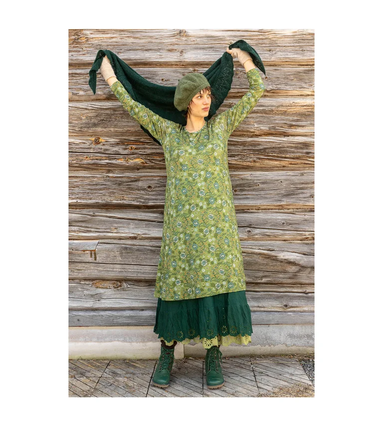 A woman wearing a green, patterned dress and a green beret from Gudrun Sjödén’s 2025 Christmas collection.