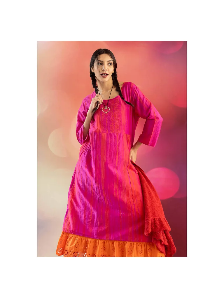 Une femme portant une robe rose brillante et un collier en argent provenant de la collection de Noël 2025 de Gudrun Sjödén.