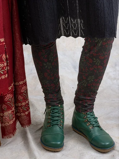 A woman wearing patterned leggings and green boots from Gudrun Sjödén.