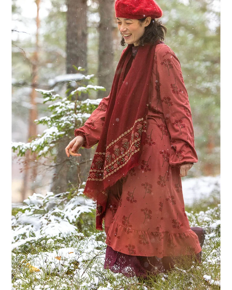 A woman wearing a red dress, shawl and beret from Gudrun Sjödén.