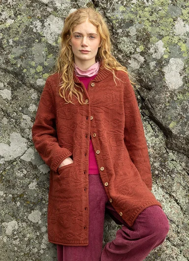 A woman wearing a brown-orange cardigan from Gudrun Sjödén.