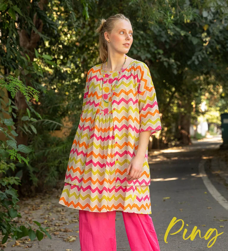 Een vrouw gekleed in een gedessineerde jurk en een blouse van Gudrun Sjödén.