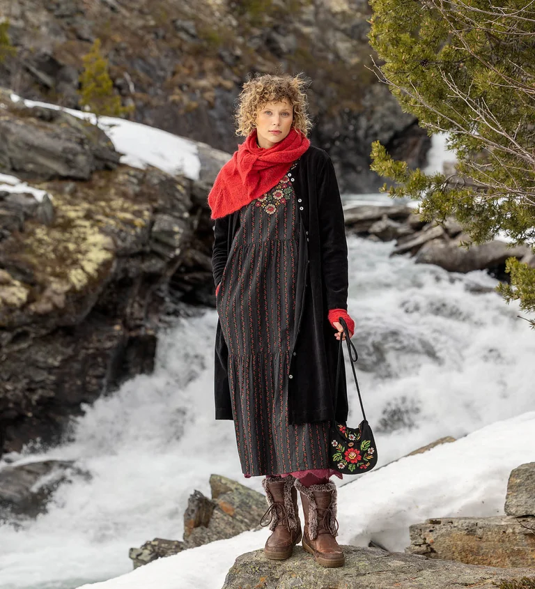 A woman standing next to a rapid wearing layers of clothes from Gudrun Sjödén’s 2025 Christmas collection.