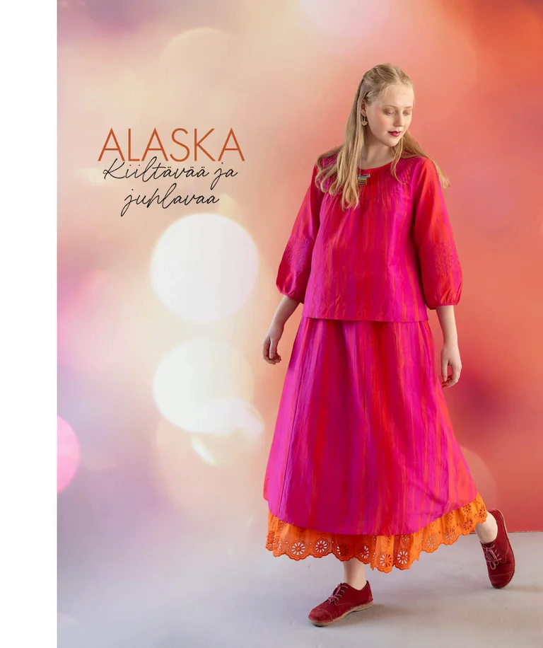 Gudrun Sjödénin vuoden 2025 joulumalliston hohtavaan roosaan puseroon ja yhteensopivaan hameeseen pukeutunut nainen.