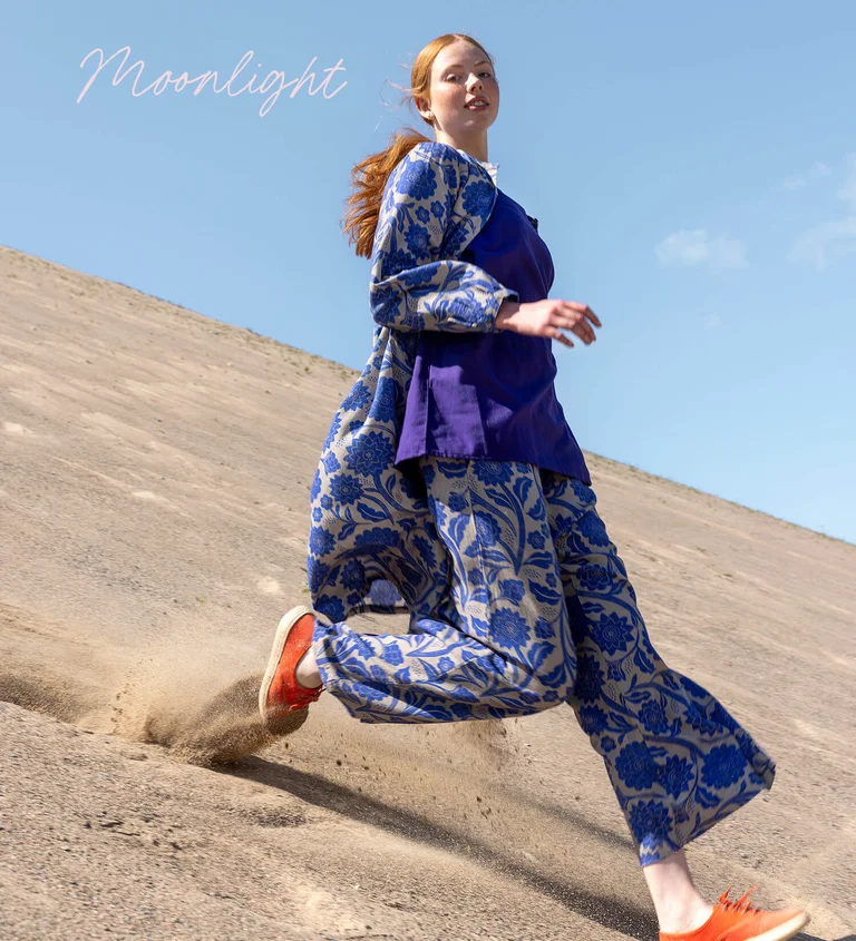 A woman wearing a patterned dress and pants from Gudrun Sjödén.