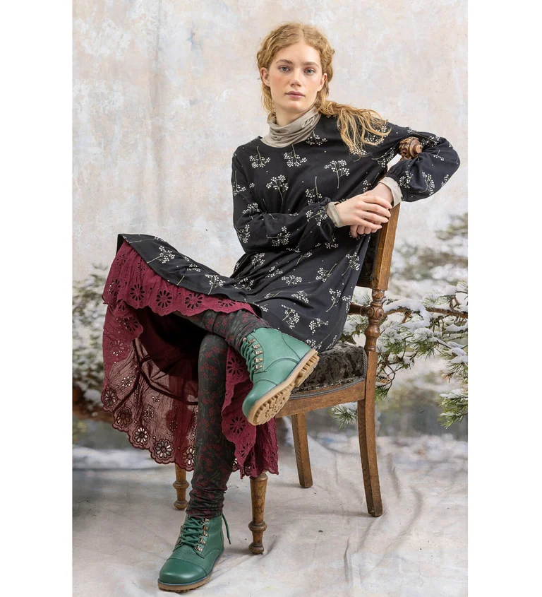 A woman wearing a patterned dress and leggings from Gudrun Sjödén.
