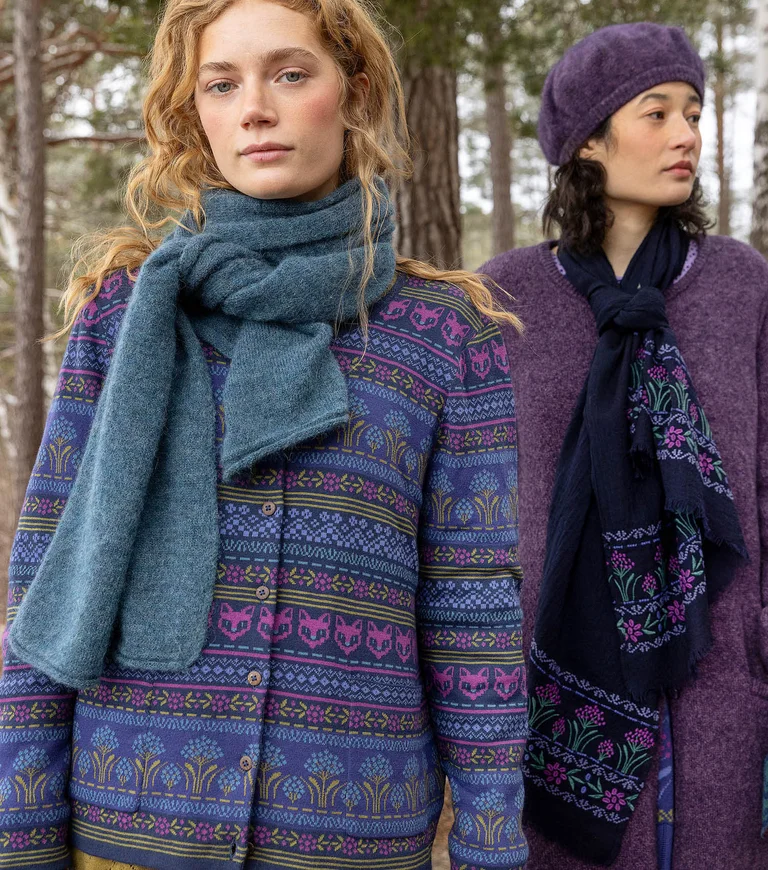 Two women wearing layers of clothing and accessories in shades of violet blue from Gudrun Sjödén.