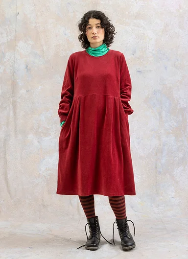 A woman wearing a red velour dress from Gudrun Sjödén.