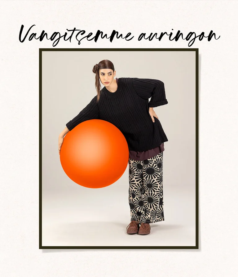 A woman wearing black and white clothing from Gudrun Sjödén, holding a large red ball.