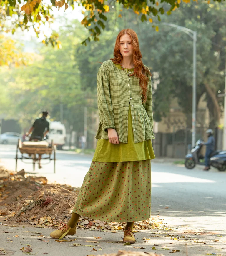 A woman wearing layers of green clothing from Gudrun Sjödén.