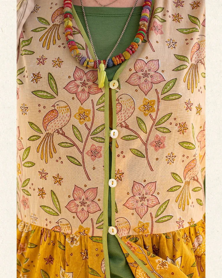 A woman wearing a yellow floral dress from Gudrun Sjödén.