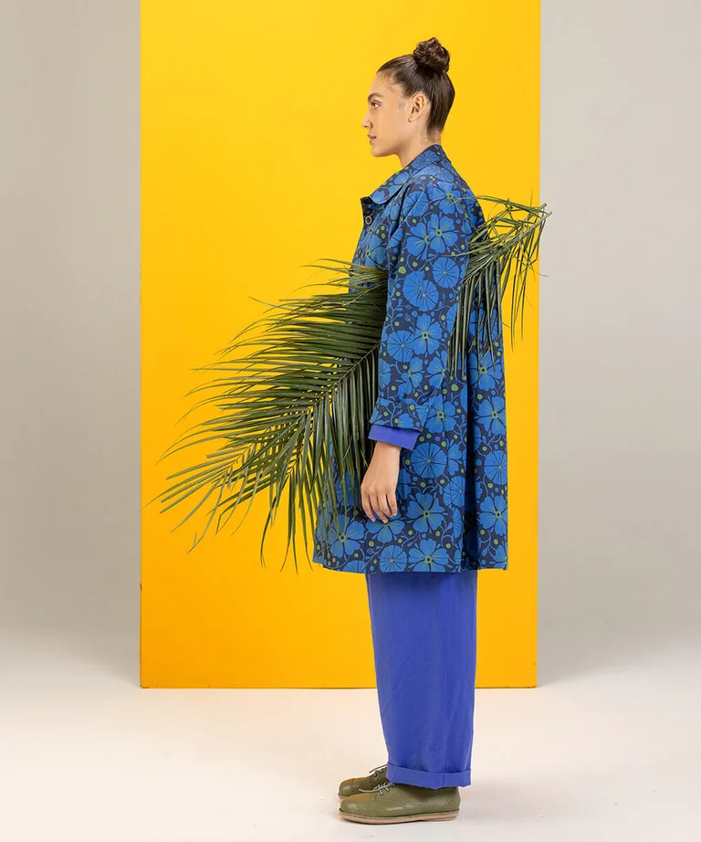 A woman photographed from the side wearing a patterned blue coat from Gudrun Sjödén.