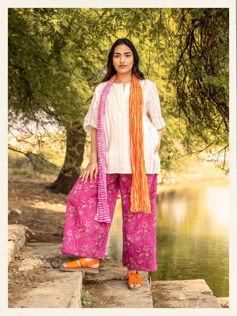 A woman wearing a linen blouse, floral trousers and a patterned scarf from Gudrun Sjödén.