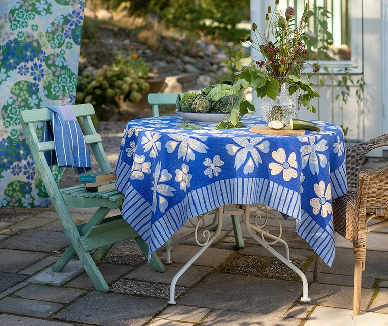 An outdoor space with blue patterned home textiles from Gudrun Sjödén.