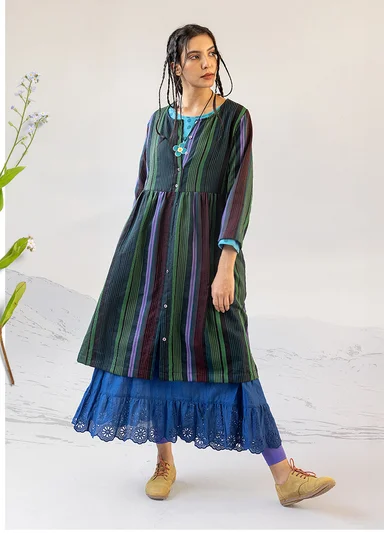 A woman wearing a striped dress and a blue underskirt from Gudrun Sjödén’s 2025 Christmas collection.