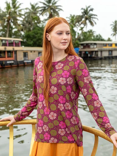 A woman wearing a pink-red patterned top from Gudrun Sjödén.