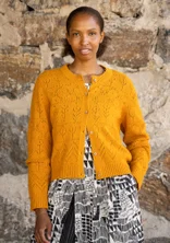 Cardigan à manches longues avec technique de tricotage pointelle dans la couleur orange. Combiné avec une robe à motifs noirs et blancs en dessous.
