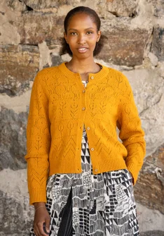 Langarmstrickjacke mit Pointelle-Stricktechnik in der Farbe orange. Komibiniert mit einem schwarz-weiss gemusterten Kleid darunter. 