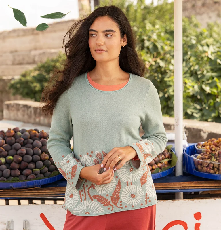 A woman wearing a knitted jumper with a floral pattern from Gudrun Sjödén. 