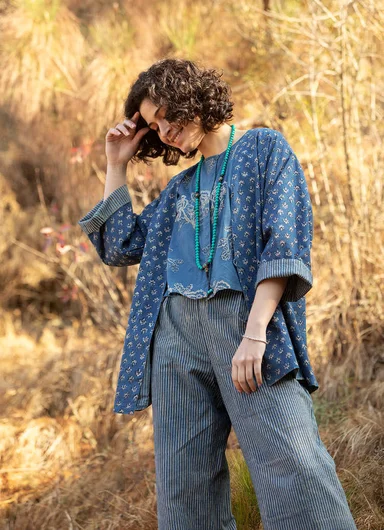 A woman in a field of corn wearing layers of clothes from Gudrun Sjödén’s Natural dyes. collection.