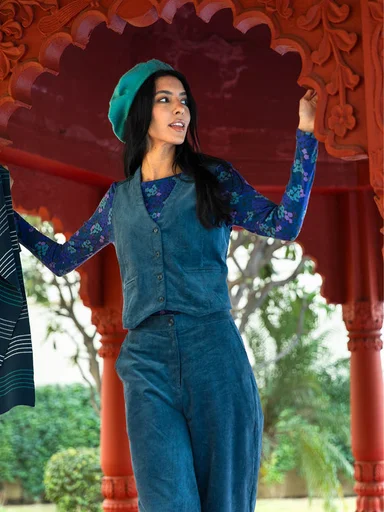 A woman wearing a woven waistcoat and woven trousers in a green-blue shade from Gudrun Sjödén.