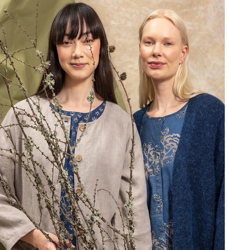 Two women standing close together wearing blue and beige clothes from Gudrun Sjödén’s “Natural dyes” collection.