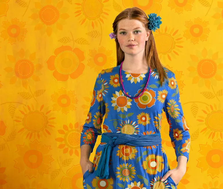 A woman wearing a blue floral dress from Gudrun Sjödén.