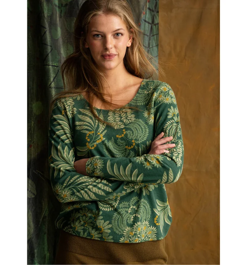 A woman wearing a green patterned top from Gudrun Sjödén.