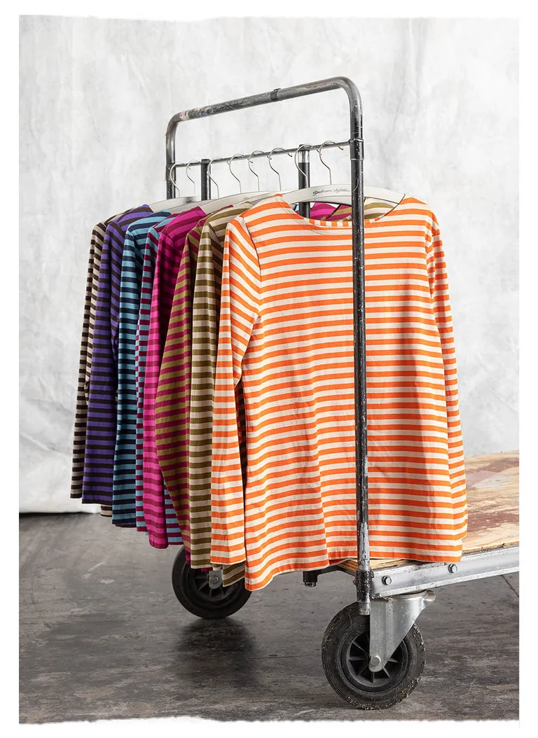 Striped sweaters from Gudrun Sjödén in a variety of colours, hanging on a clothes horse in a photo studio.