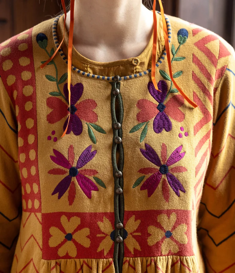 A woman wearing an embroidered yellow cardigan from Gudrun Sjödén.