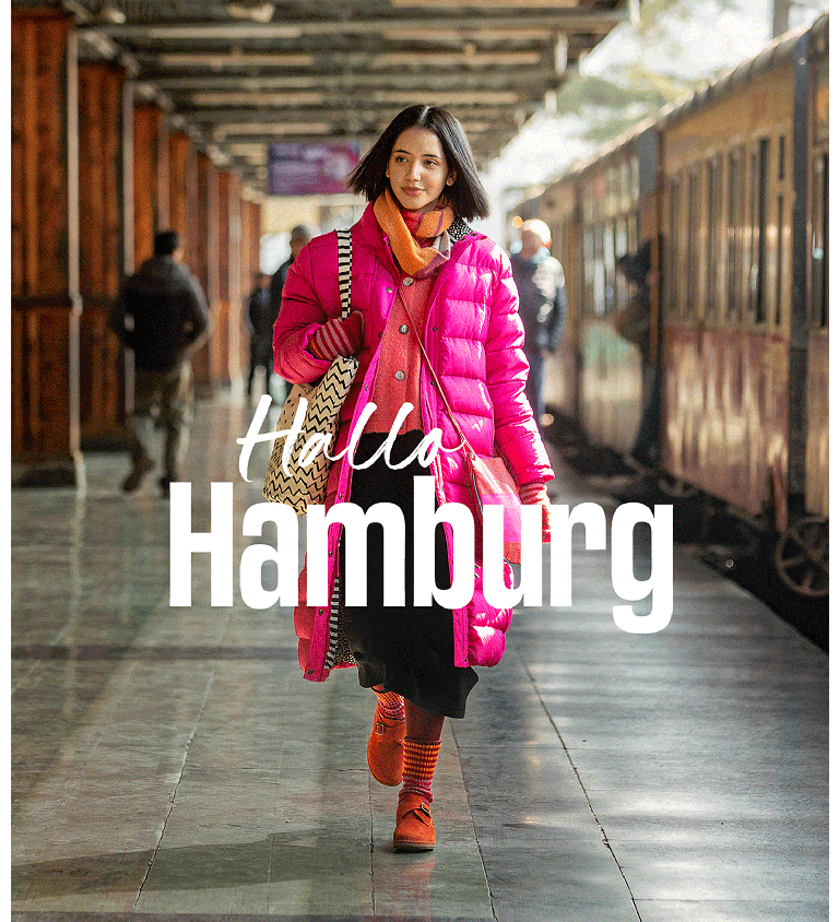 A woman walking along a railway station platform wearing layers of clothes from Gudrun Sjödén.