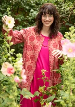 Femme portant des vêtements naturels de Gudrun Sjödén - une tunique rouge en coton avec des boutons et un motif de roses rouges.