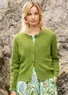 Cardigan à manches longues avec technique de tricotage Pointelle dans la couleur verte. Combiné avec une robe claire avec un motif floral dans les couleurs bleu, marron et vert. 
