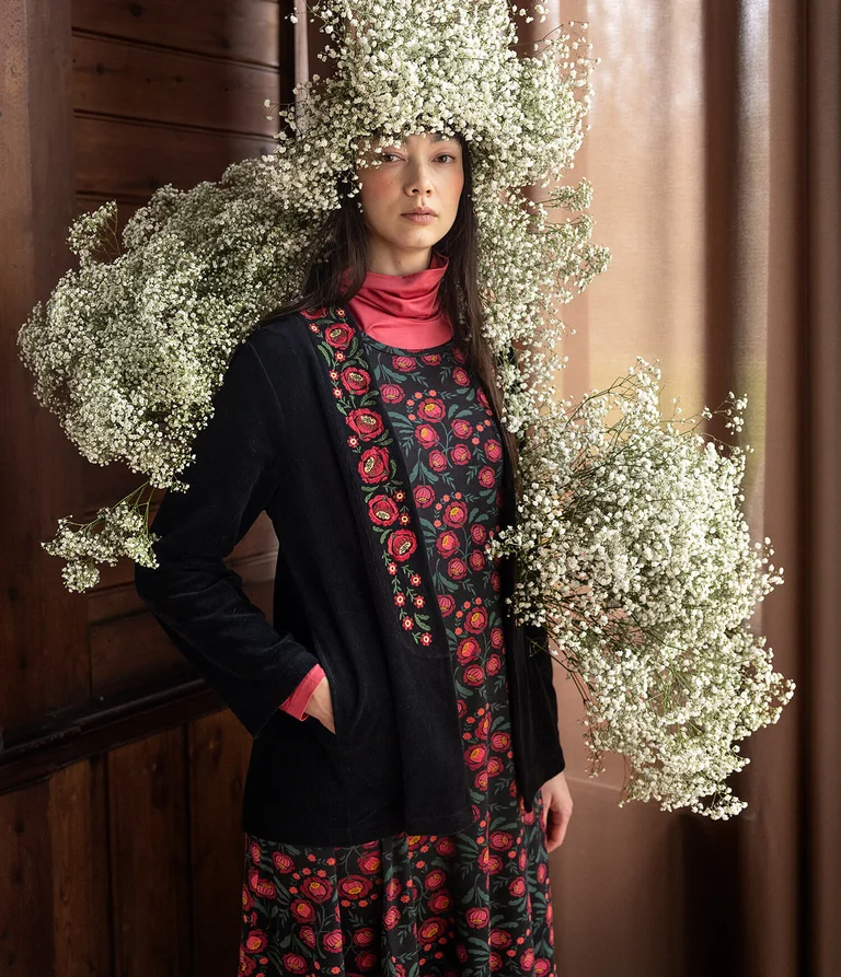 A woman wearing a floral dress and black cardigan from Gudrun Sjödén.  