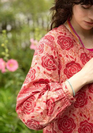 Frau trägt rote Tunika aus Bio-Baumwolle mit einem roten Blumenmuster. 