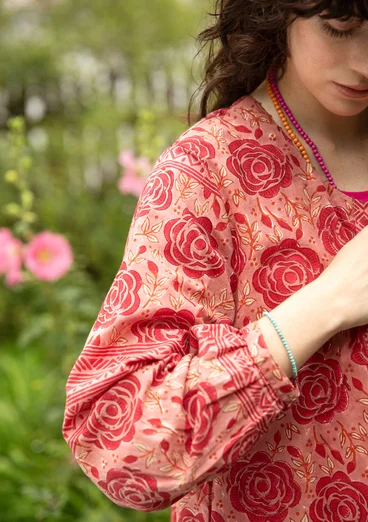 Femme portant une tunique rouge en coton bio avec un motif floral rouge.