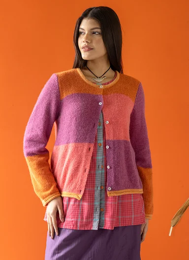 A woman wearing a colourful block-pattern cardigan from Gudrun Sjödén.