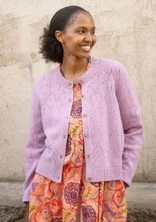 Cardigan à manches longues avec technique de tricotage pointelle dans la couleur lilas. Combiné avec une robe orange avec un motif floral coloré. 
