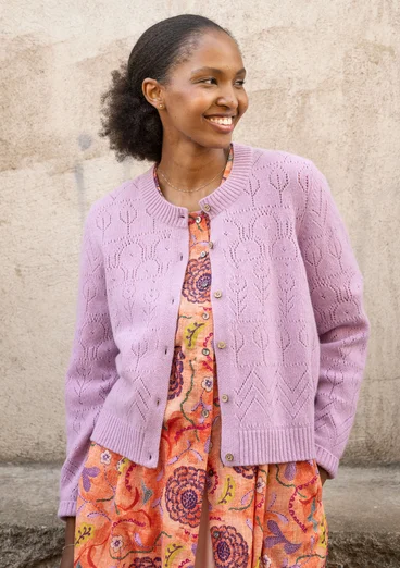 Langarmstrickjacke mit Pointelle-Stricktechnik in der Farbe flieder. Komibiniert mit einem  orangenen Kleid mit buntem Blumenmuster. 