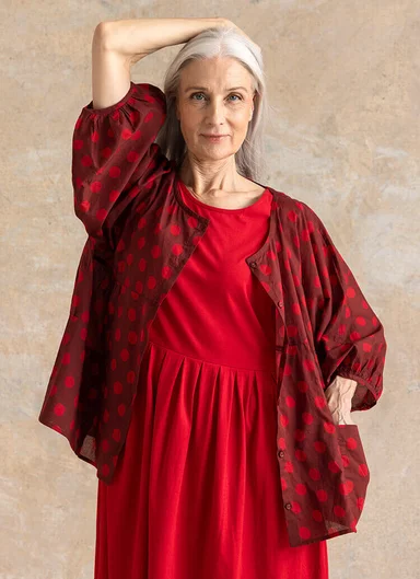 A woman in a studio wearing layers of woven clothes from Gudrun Sjödén.