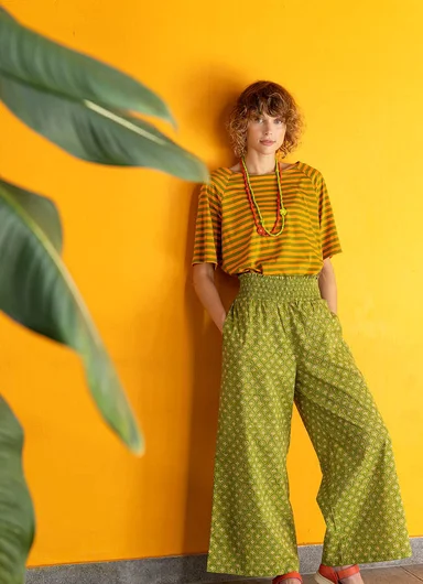 A woman wearing a yellow blouse and a floral jersey dress from Gudrun Sjödén.