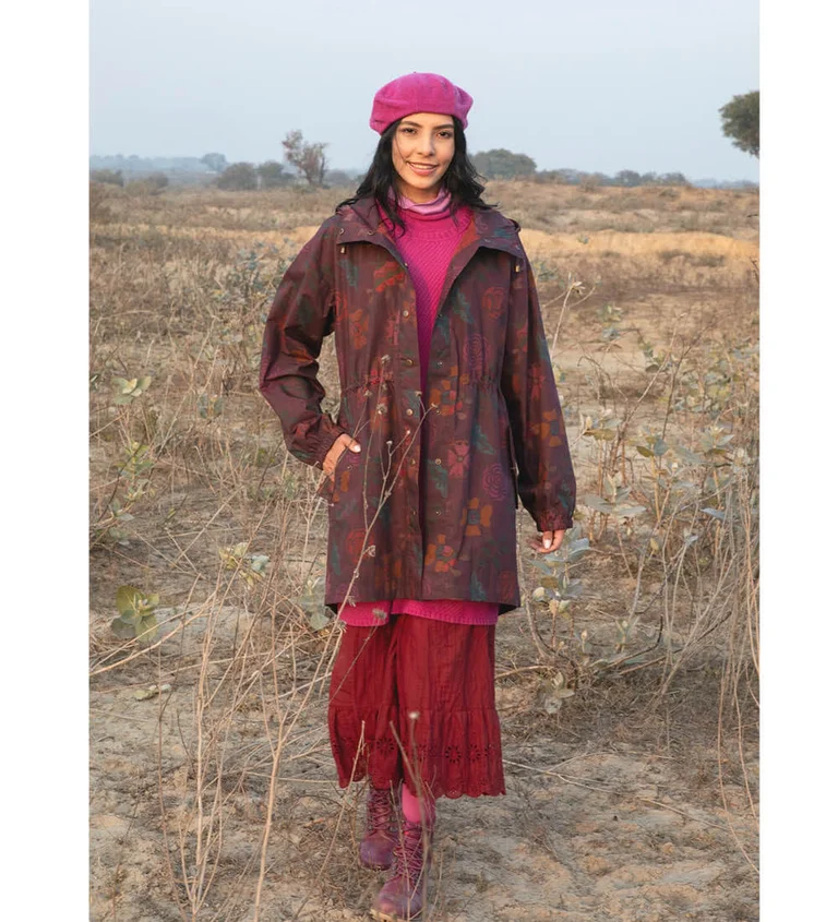 A woman outdoors wearing a patterned parka in burgundy tones from Gudrun Sjödén.